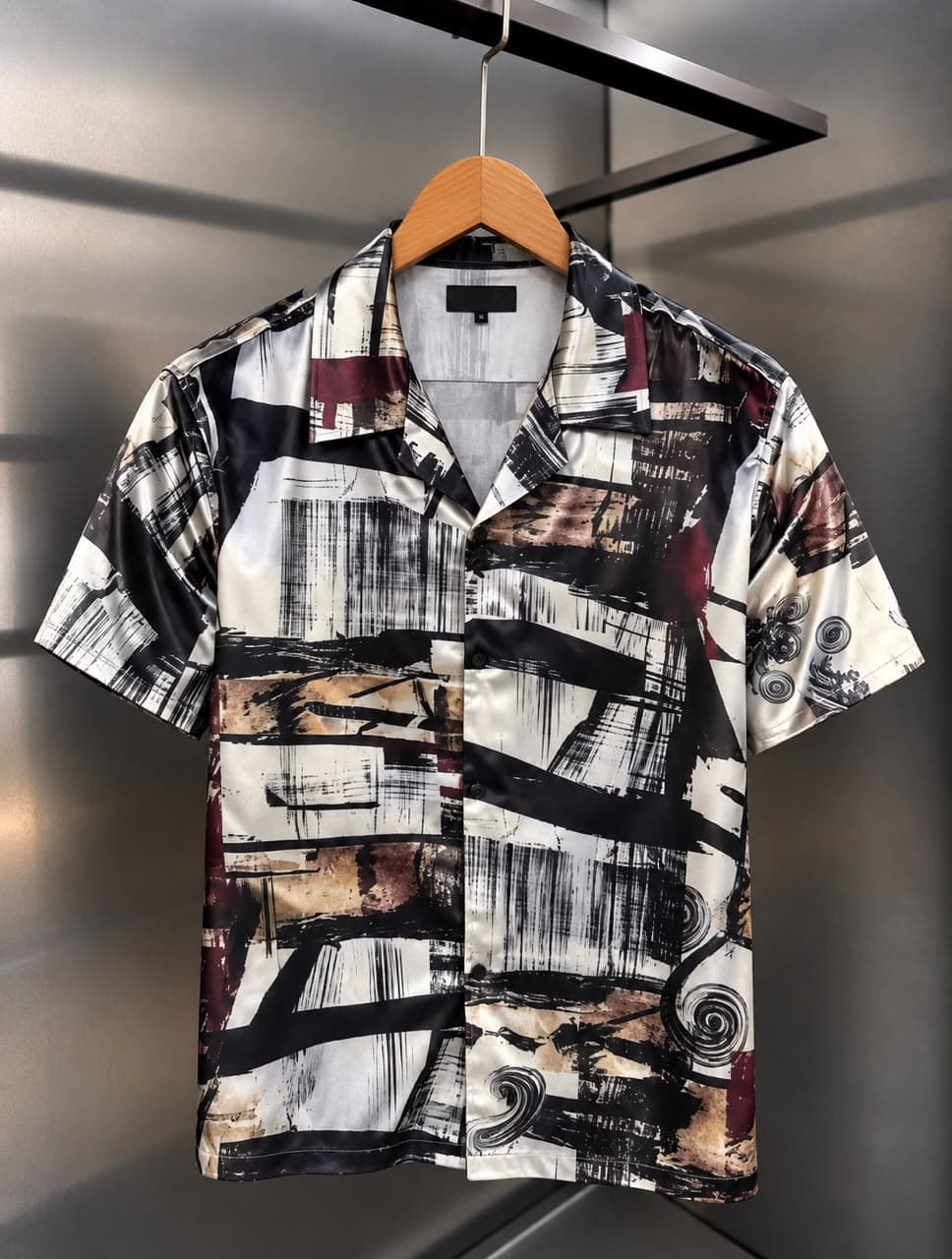 Front view of short-sleeved satin shirt with teal, green, yellow, and orange abstract wave print.