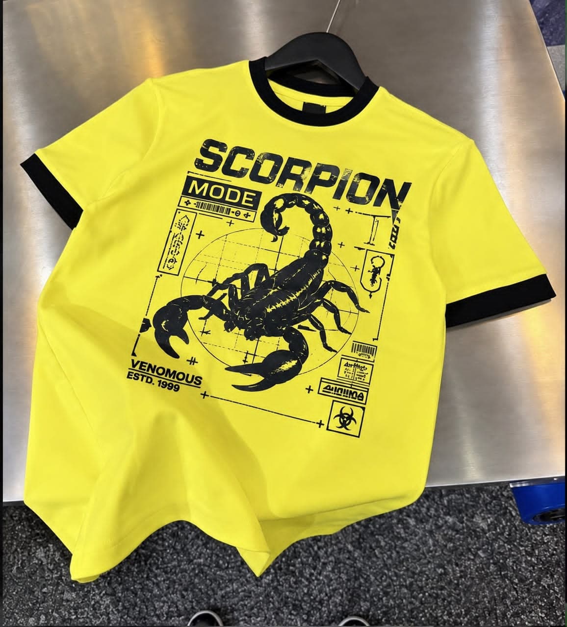 Flat lay front view of yellow scorpion mode graphic t-shirt with black scorpion and text details.