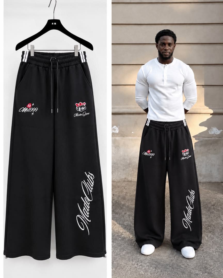 Black MadeClubs joggers with multiple embroidered graphics shown on hanger and model.