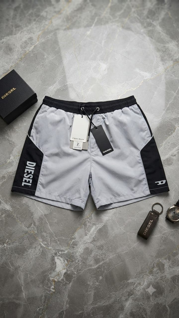Gray and black Diesel colorblock shorts with side logo and tags on marble floor.