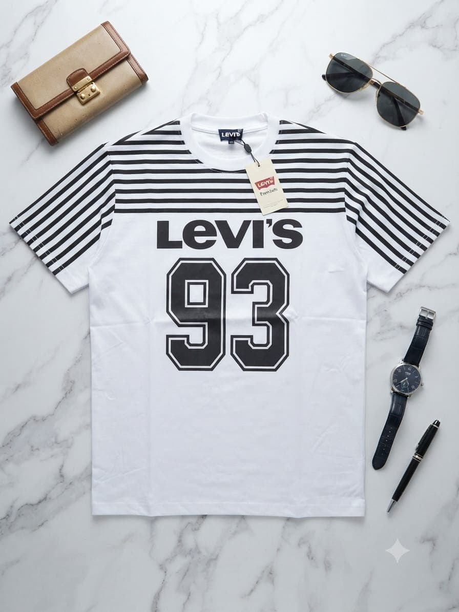 Black Off White graphic t-shirt on marble with luxury bags and watch.