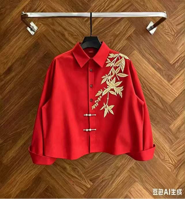 Red cropped button-up shirt with gold leaf embroidery on wooden background.