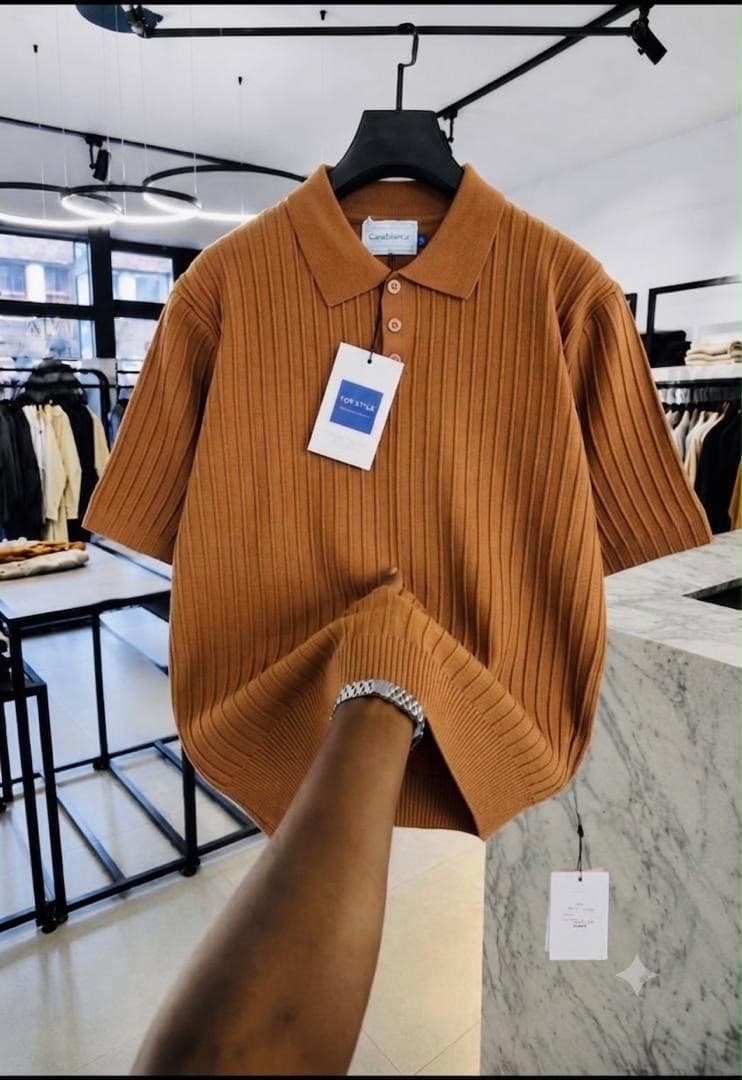 Brown ribbed knit polo shirt held by the hem.