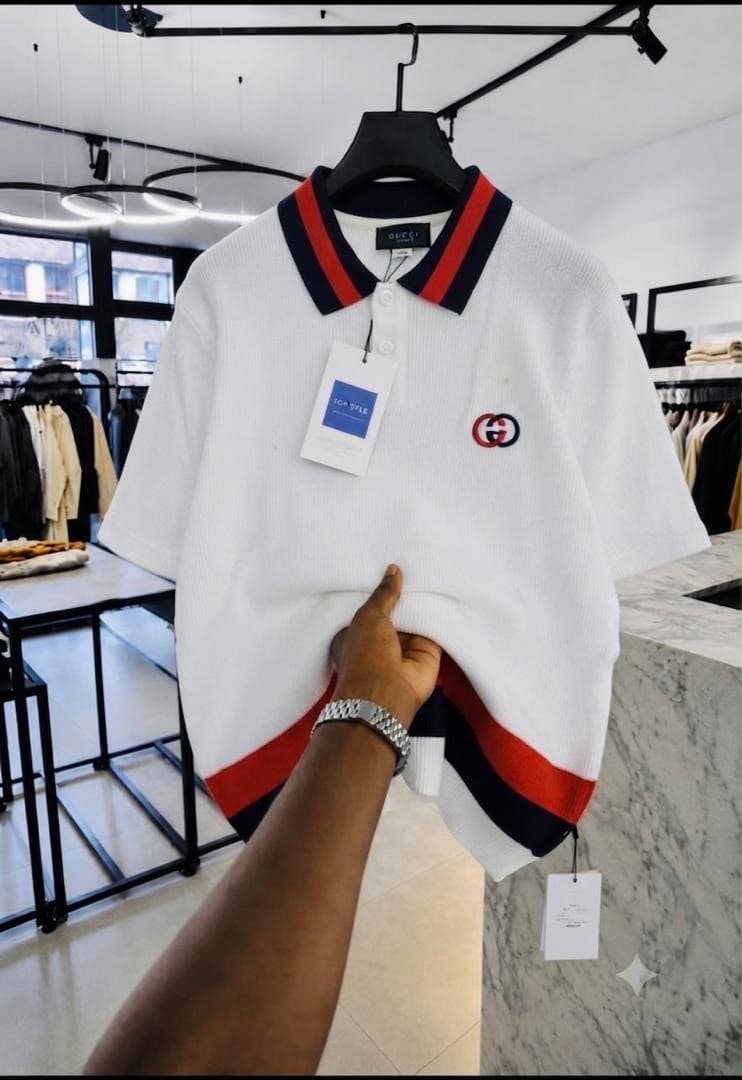 White Gucci GG ribbed polo shirt with red and navy striped collar.
