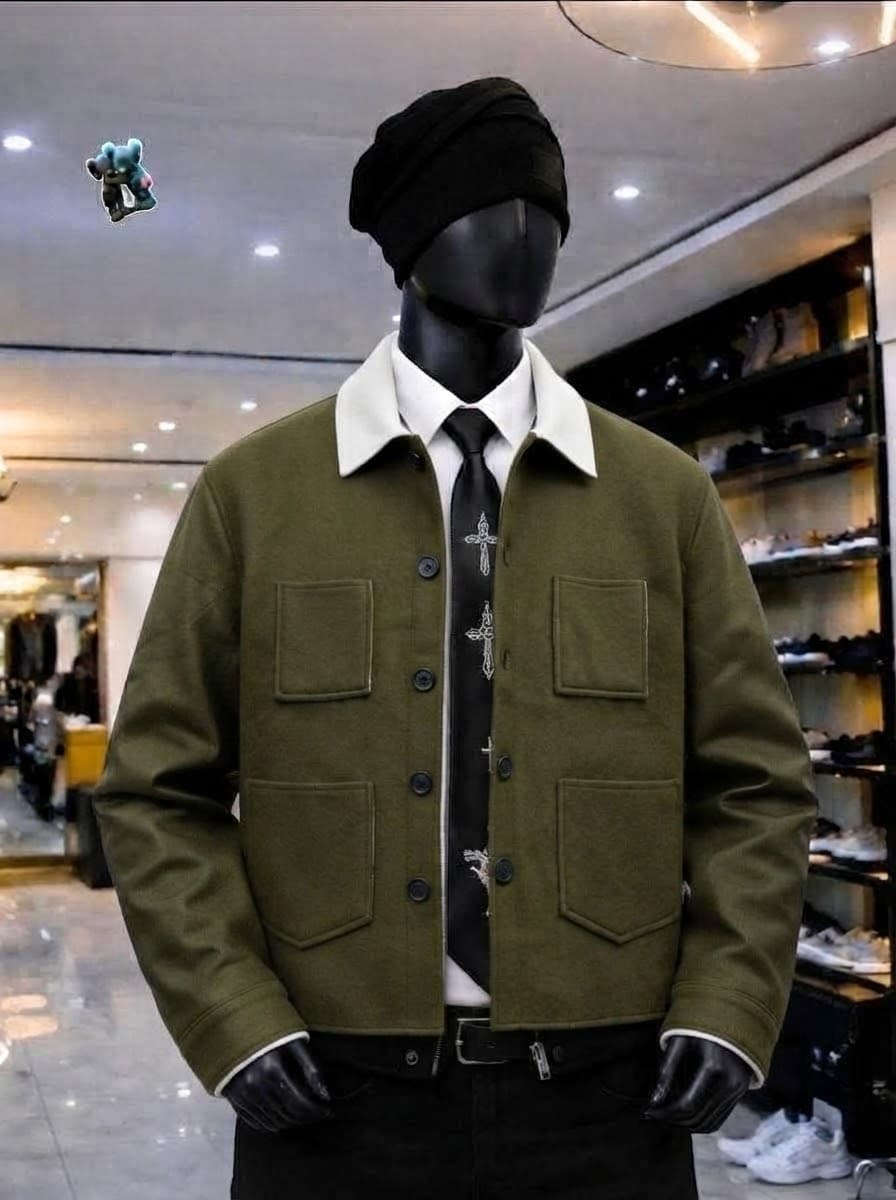 Flat lay of olive green wool jacket with white contrast collar, cuffs and lining on marble surface.