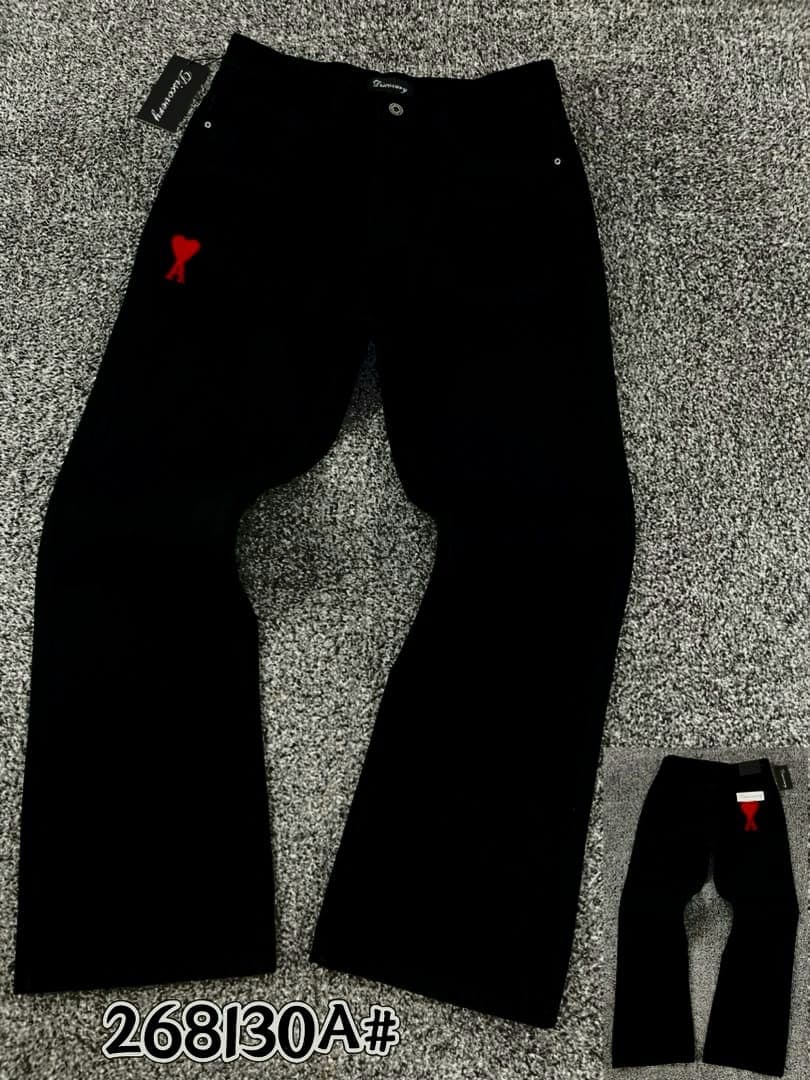 Black baggy jeans with red heart logo on thigh laid flat on gray surface, front and back views shown.