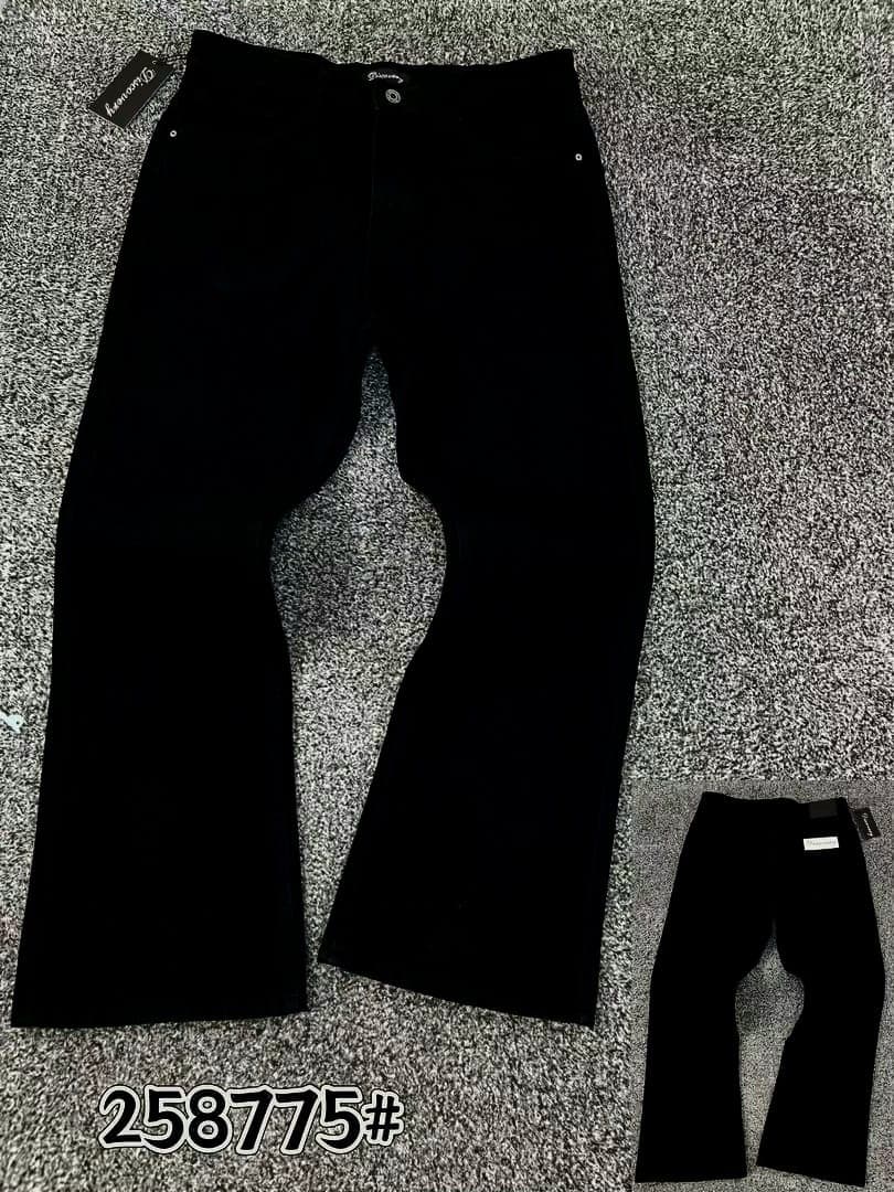 Black baggy flared jeans laid flat on textured gray surface showing front view with brand tag.
