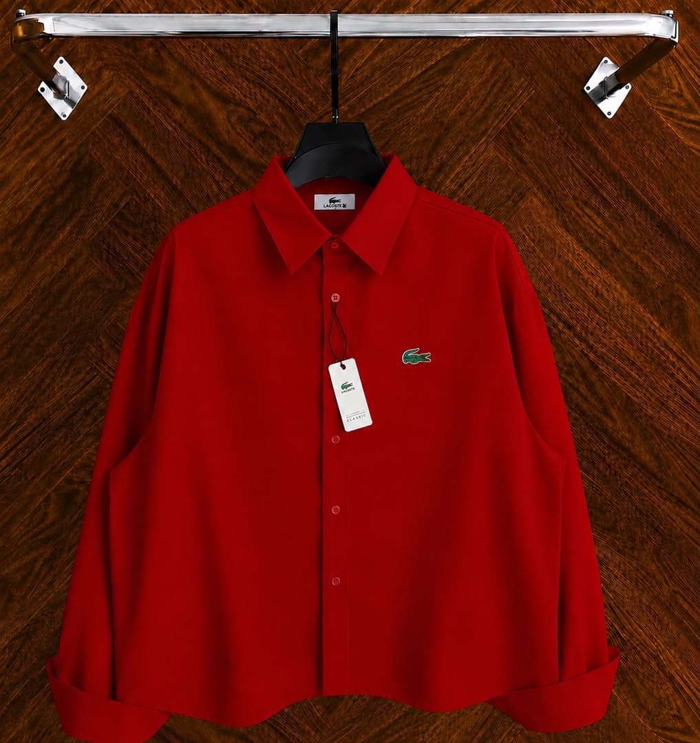 Red Lacoste long sleeve button-down shirt featuring embroidered crocodile logo displayed on hanger.