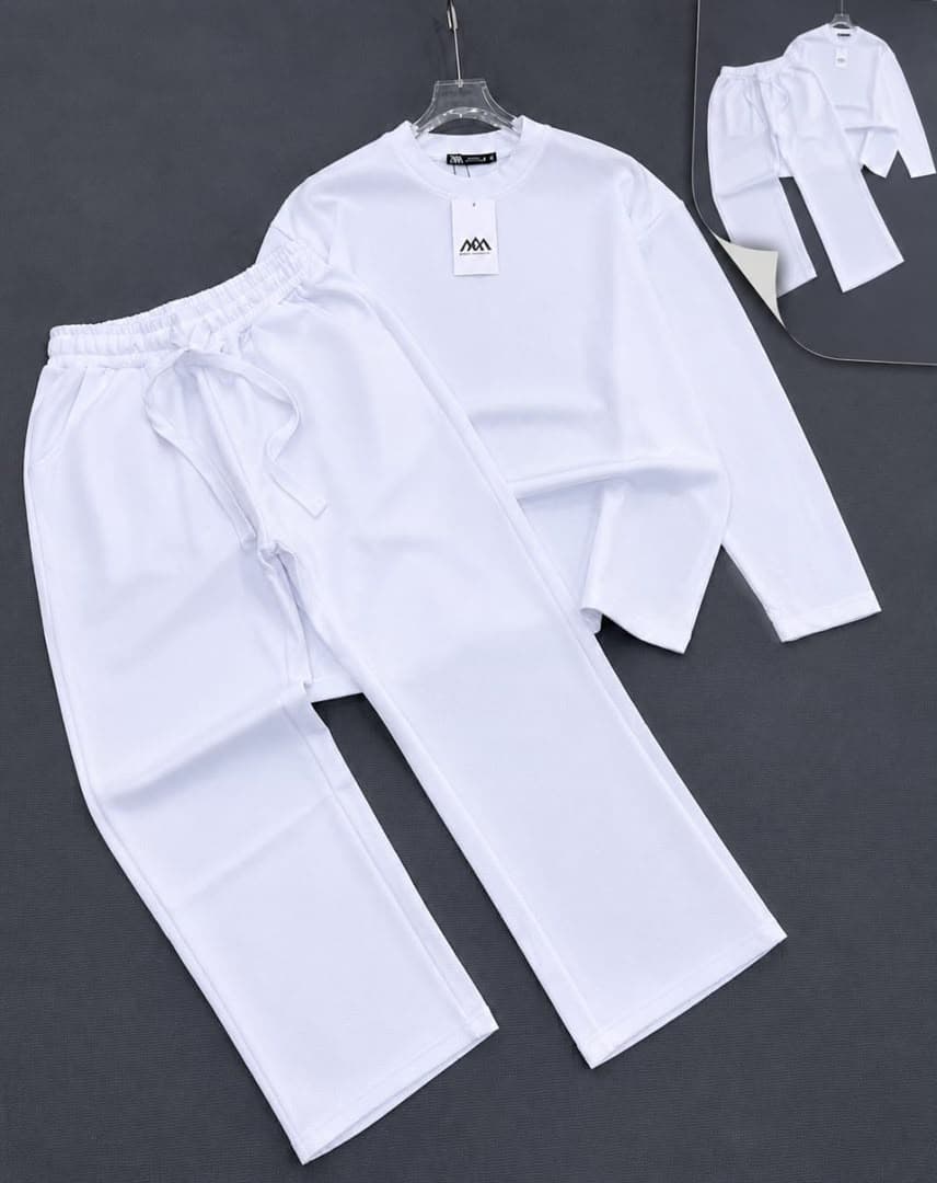 White textured knit two-piece set with long sleeve top and pants on dark background.