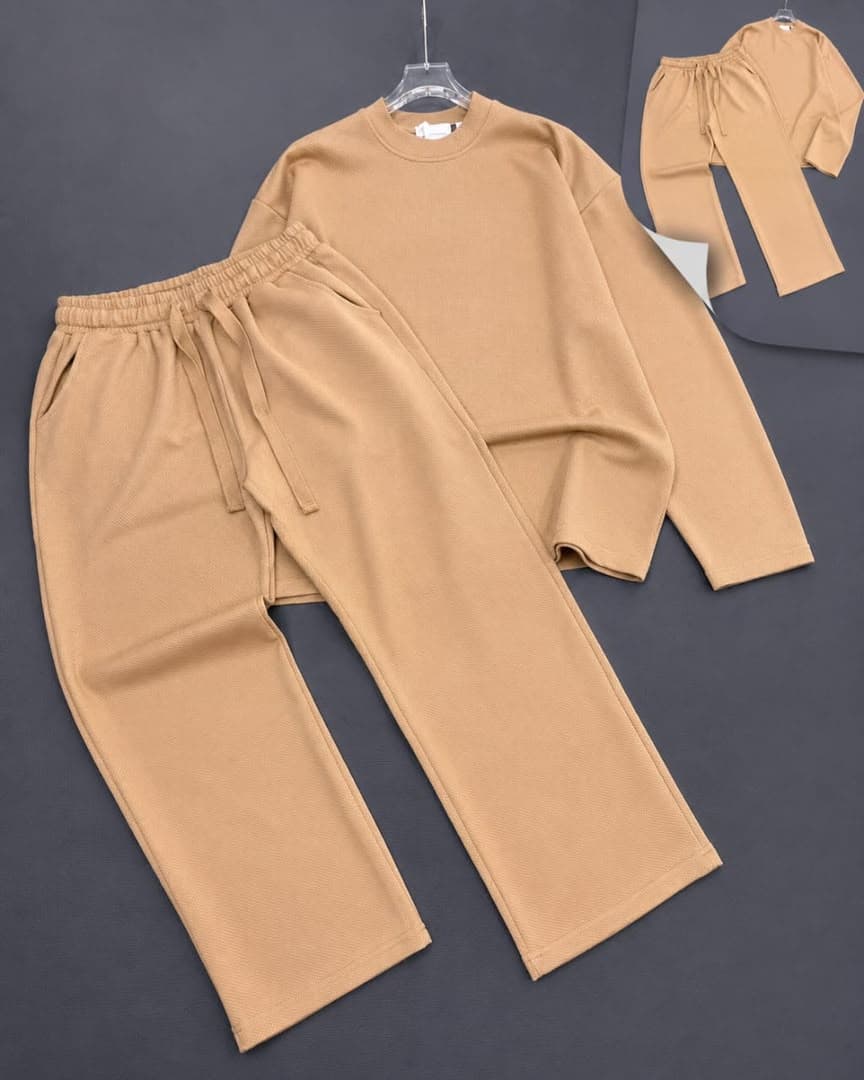 Beige textured knit two-piece set with long sleeve top and pants on dark background.