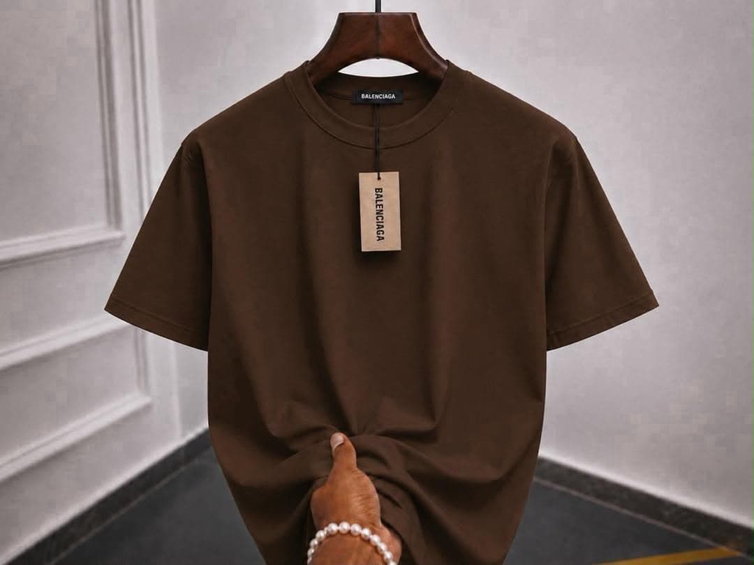 Brown plain t-shirt on hanger with hand holding bottom.