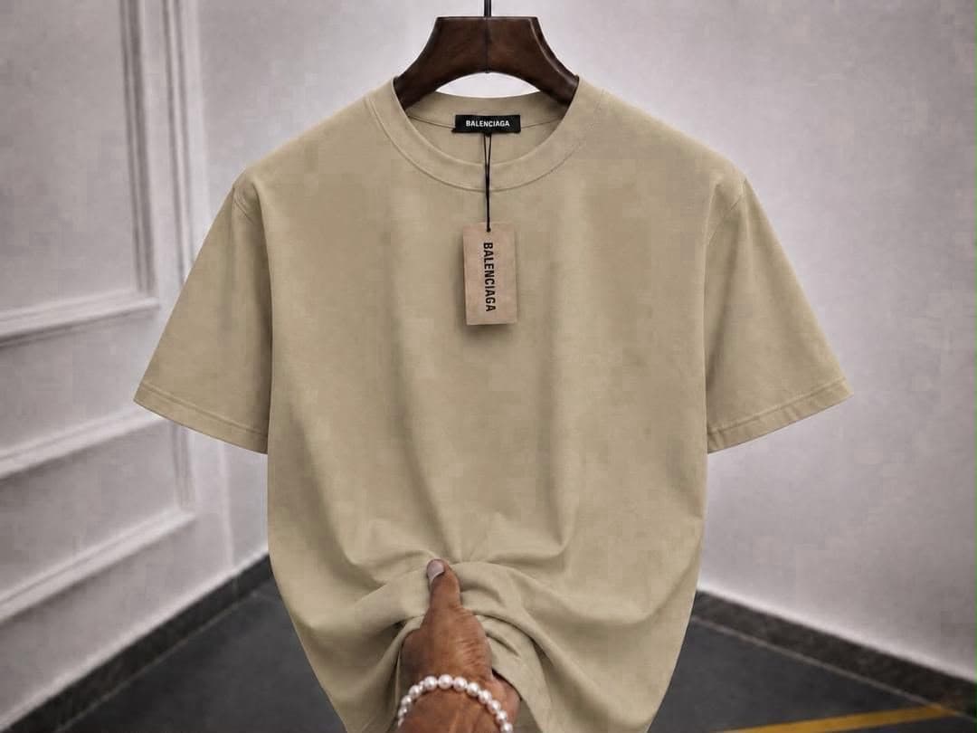 Beige plain t-shirt on hanger with hand holding bottom.