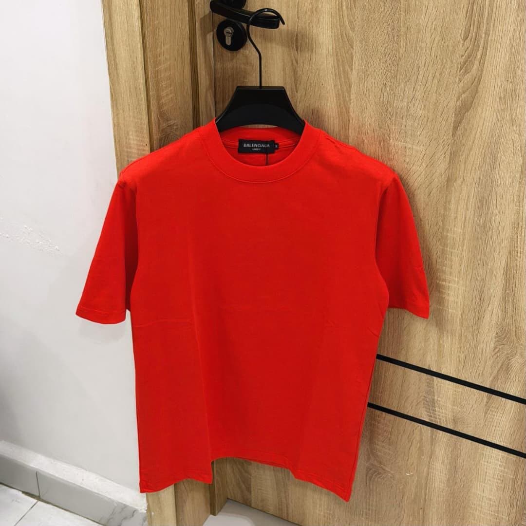 Red plain t-shirt hanging on wooden door.
