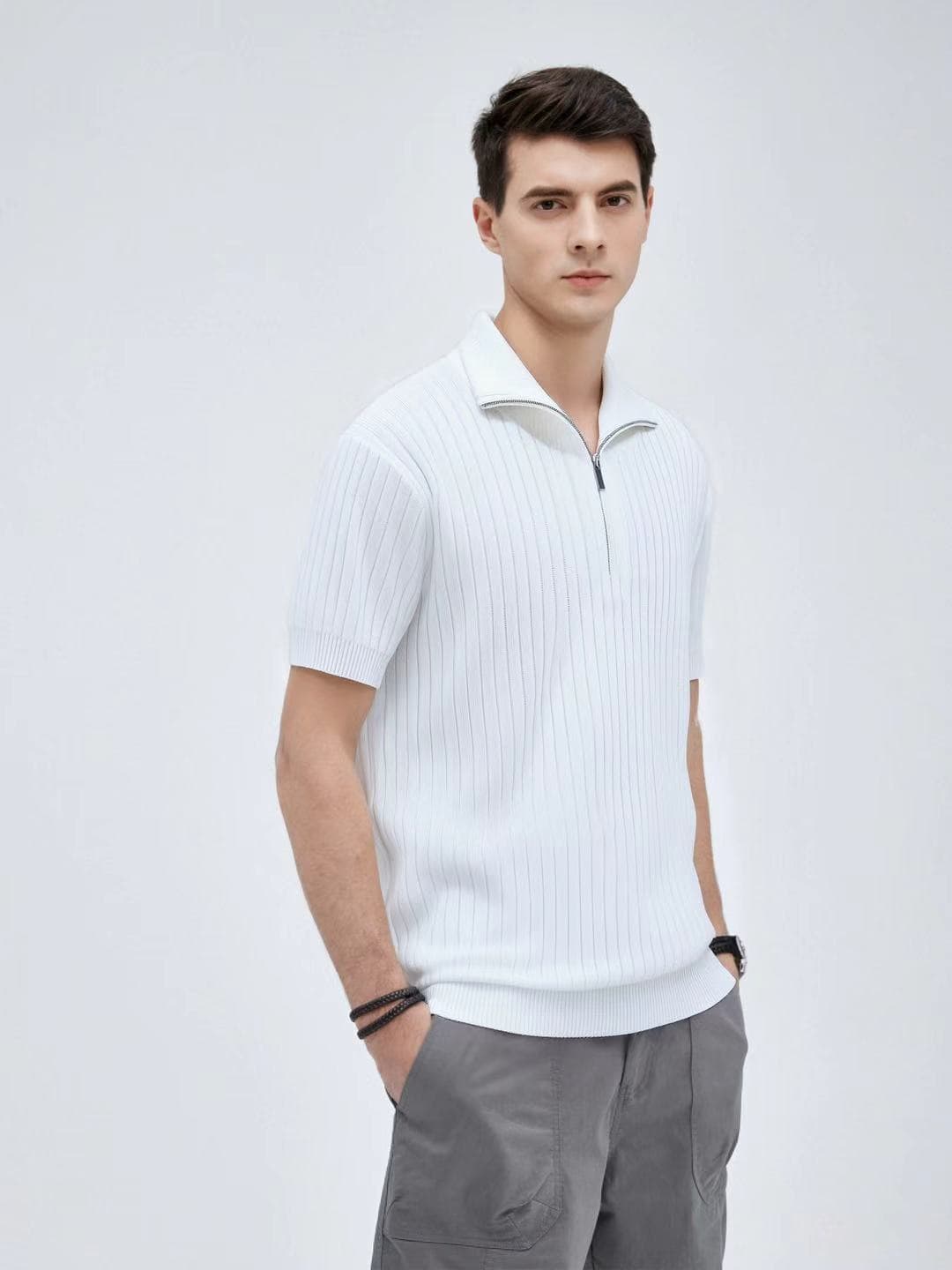 Model wearing a white ribbed knit short-sleeve quarter-zip polo shirt with grey cargo pants.