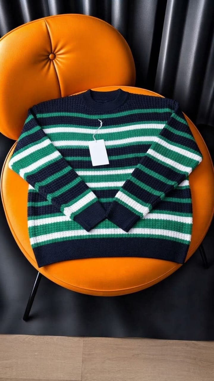 Gray striped cable knit sweater with red black white stripes on orange chair.