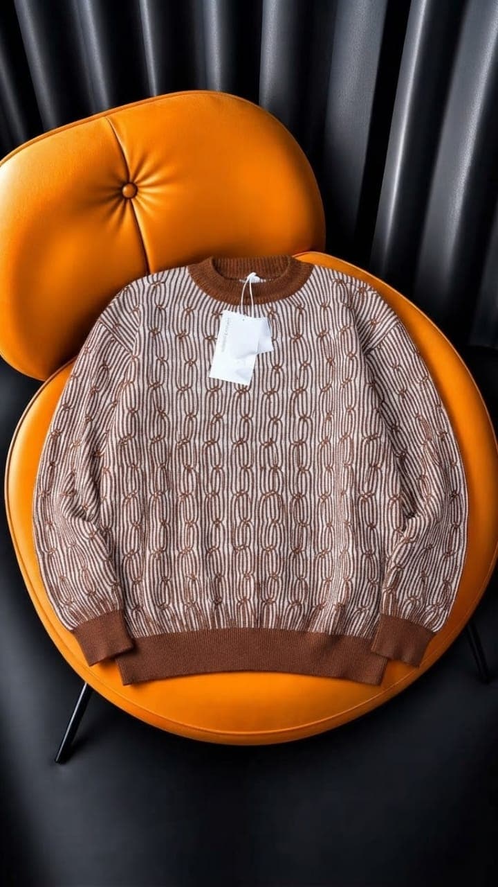 Gray LV monogram print knit sweater displayed on orange chair.