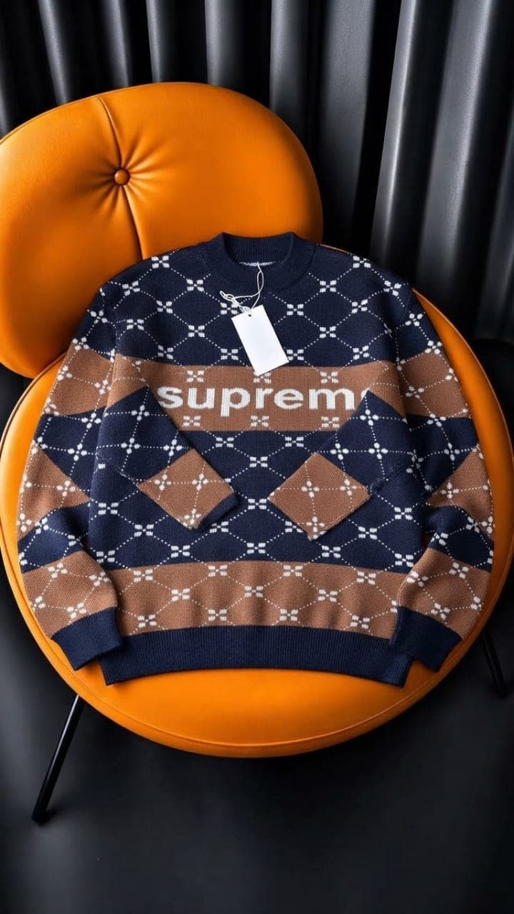 Navy ribbed knit sweater with plaid patches folded on orange chair.