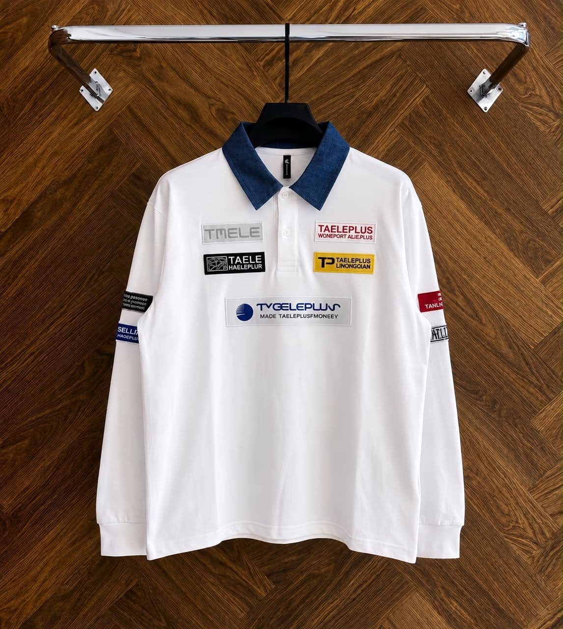 Two white long sleeve polos with denim collars and patch details hanging side by side.