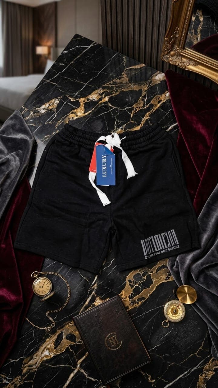 Black fleece shorts with white barcode and Create your own destiny text on marble with props.