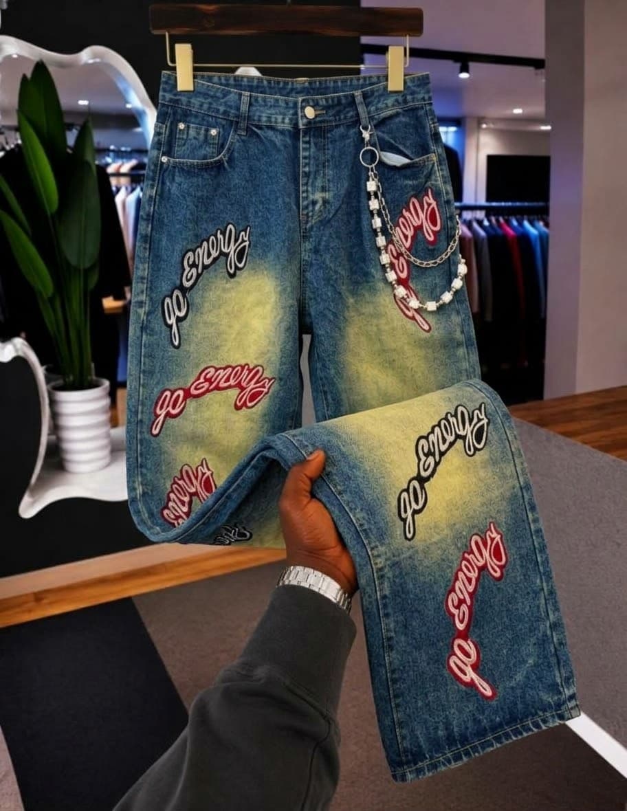 Blue denim shorts covered in silver pyramid studs, displayed on hanger and held showing details.