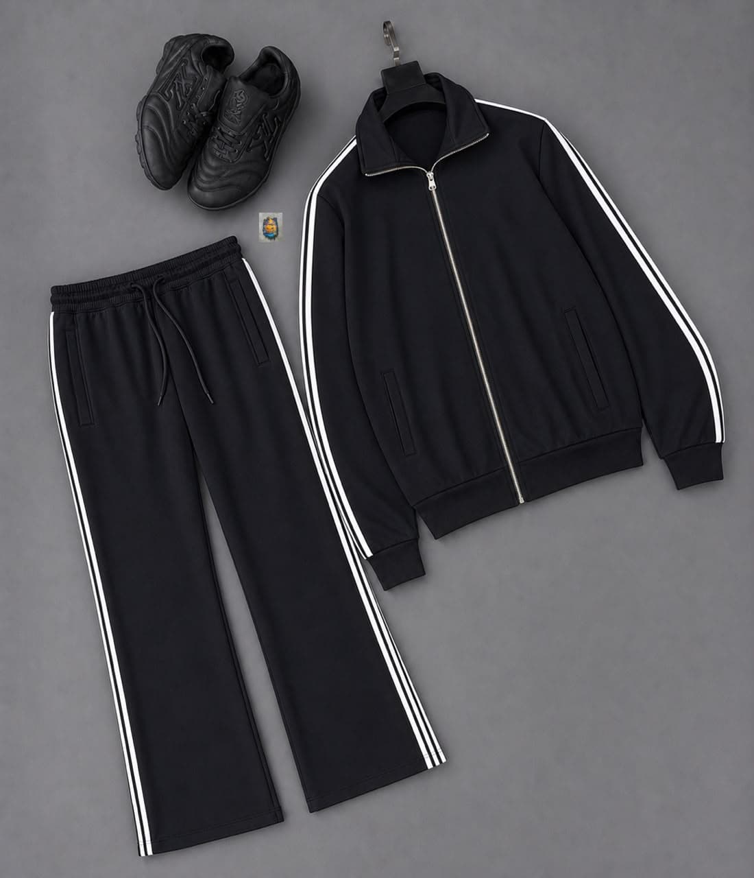 Black track suit jacket and pants with white side stripes paired with black sneakers.