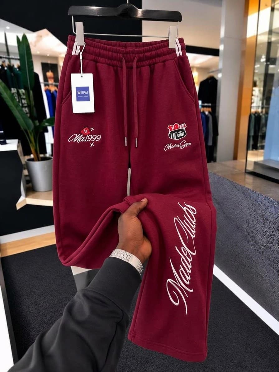Gray SEVEERS striped joggers on hanger displaying side stripes and embroidery.
