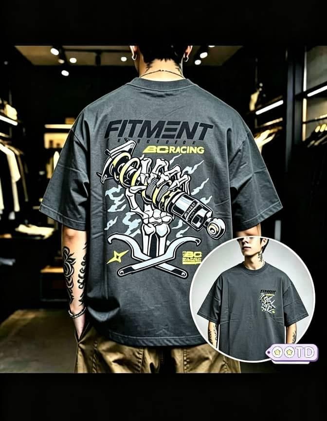 Man in gray oversized T-shirt with large Fitment 80 Racing skeleton mechanical graphic on back and front inset.