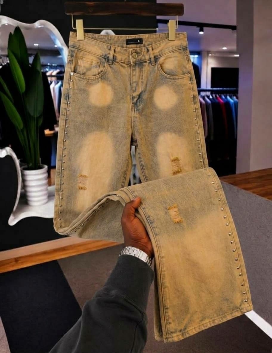 Model in dark green baggy jeans with metal hardware on fly and embroidery on legs.