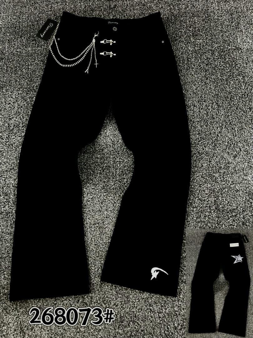 Brown baggy jeans on hanger and held by hand showing gold star studs and wash details.
