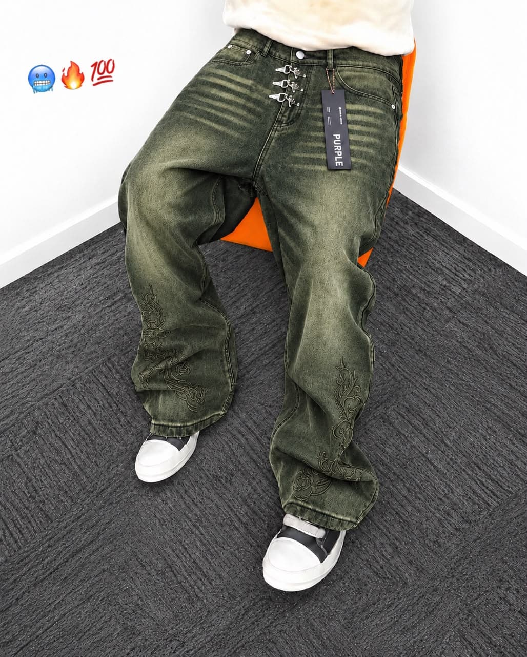 Beige baggy jeans on wooden hanger and held showing studs, rips and wash details.