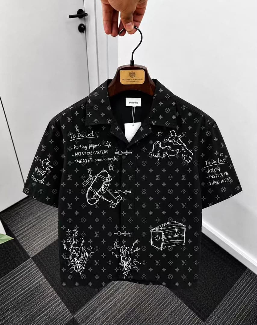 Black monogram sketch print short sleeve shirt on hanger.