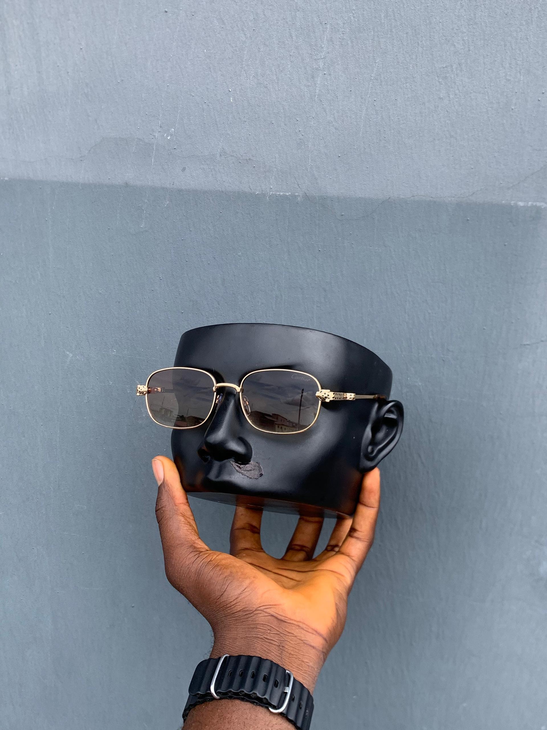 Cartier gold rectangular framed sunglasses with tinted lenses on mannequin head.