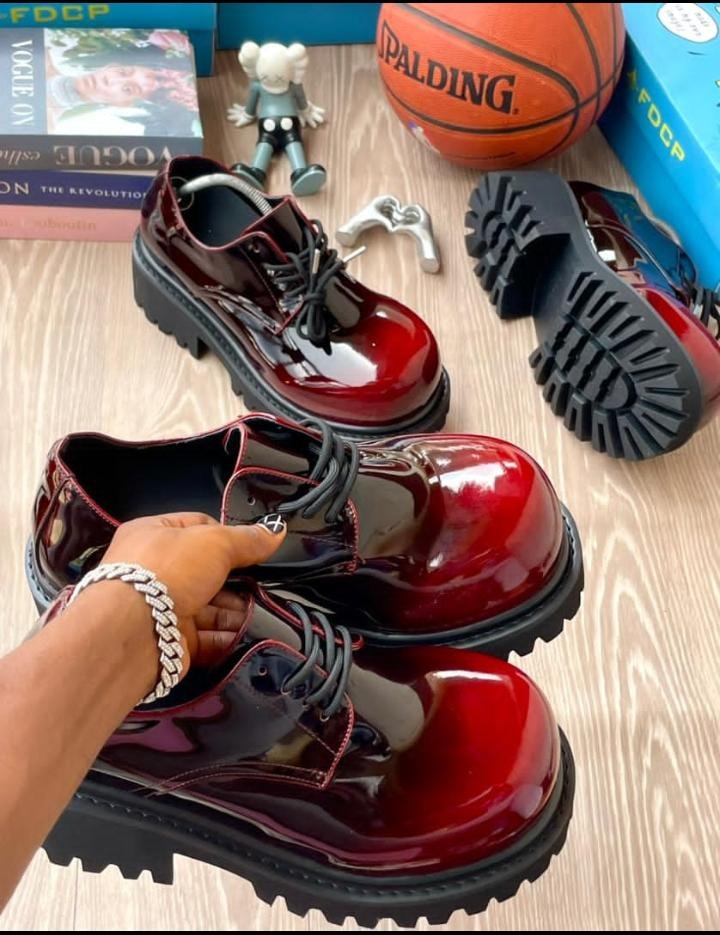 Red patent leather platform derby shoes with chunky black soles and lace-up detail.