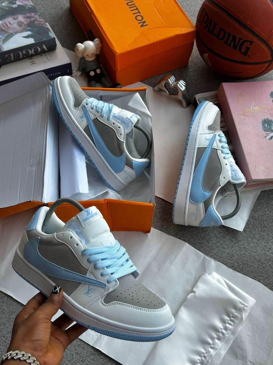Louis Vuitton x Nike Air Jordan 1 sneakers in grey blue and white with luxury boxes and props.