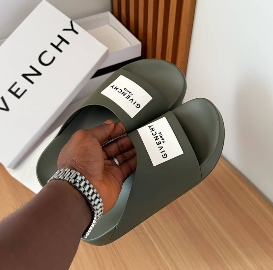 Olive green Givenchy slides held in hand with white Givenchy box.