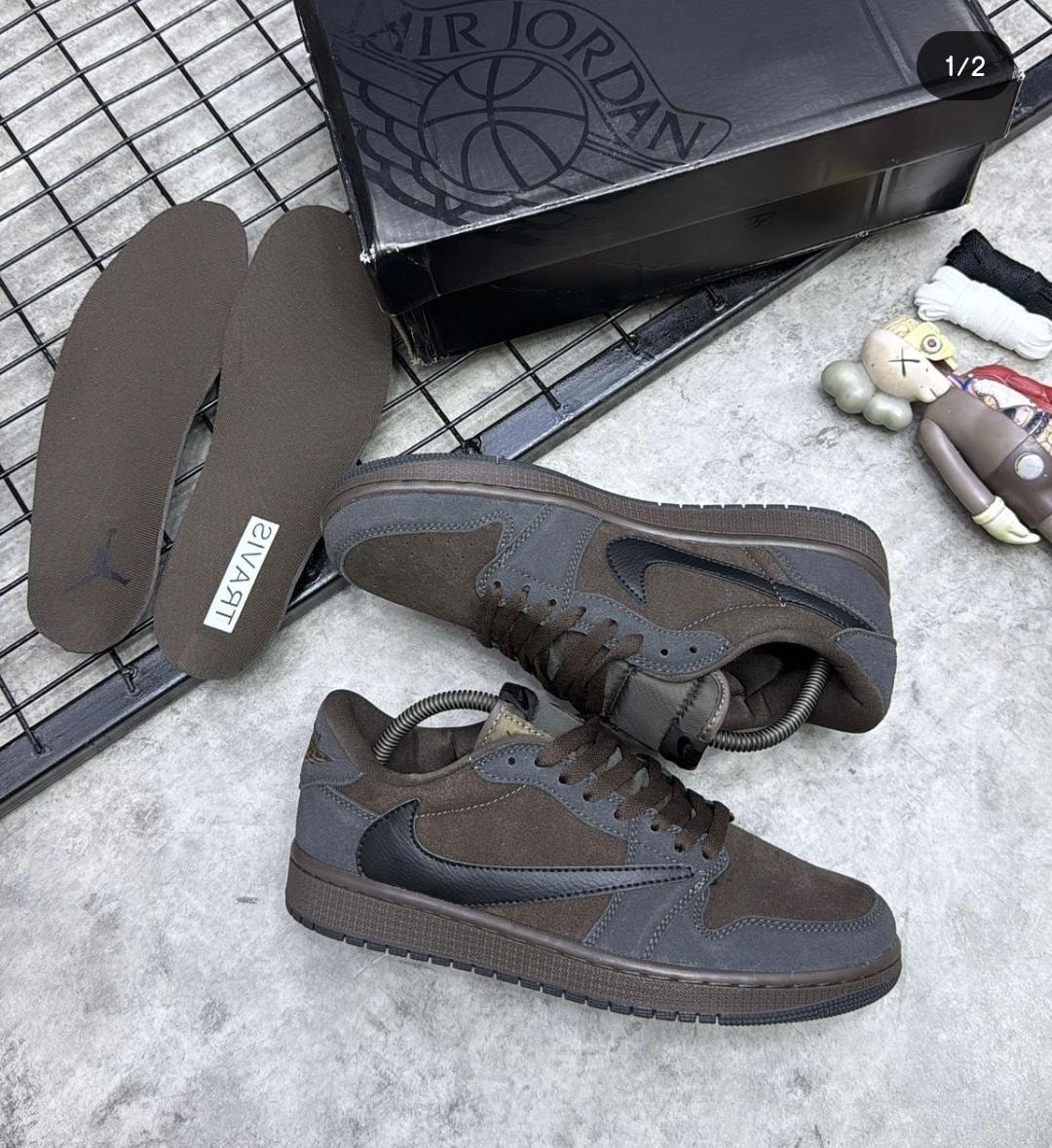 Brown and gray Nike Air Jordan 1 Low sneakers with box, insoles and accessories on grid surface.