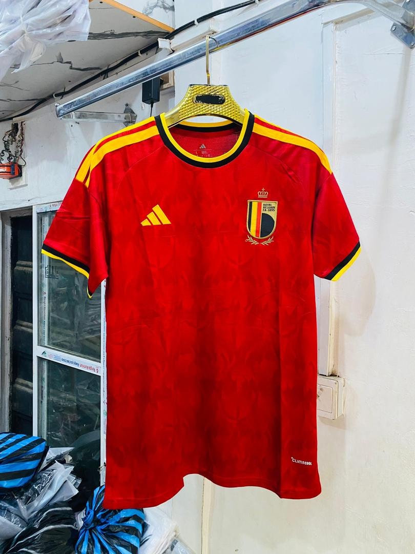 Red Belgium national soccer jersey with yellow accents hanging in a shop environment.
