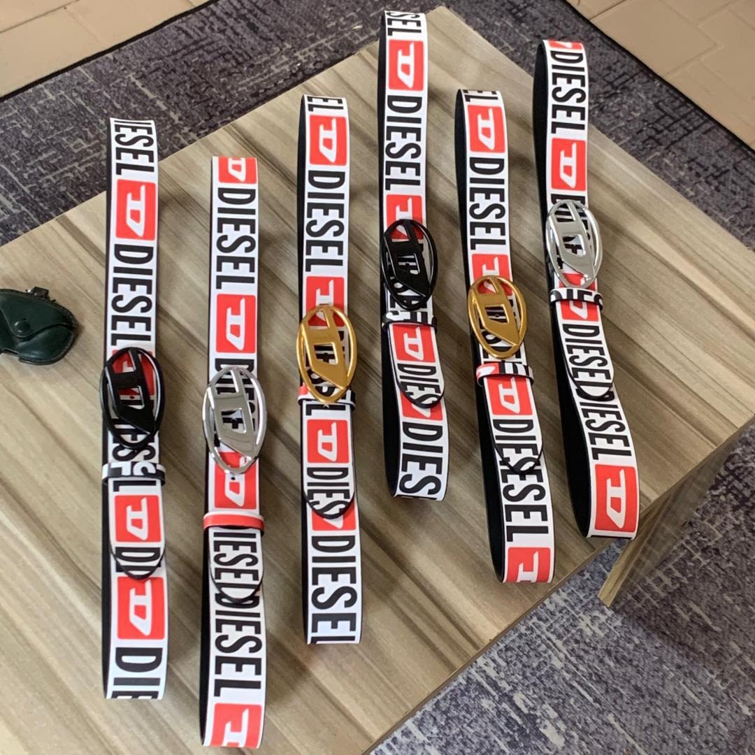 Five Diesel logo belts with different colored buckles on wooden surface.