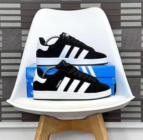 Black and white Adidas Campus low top sneakers on white chair with blue shoebox.