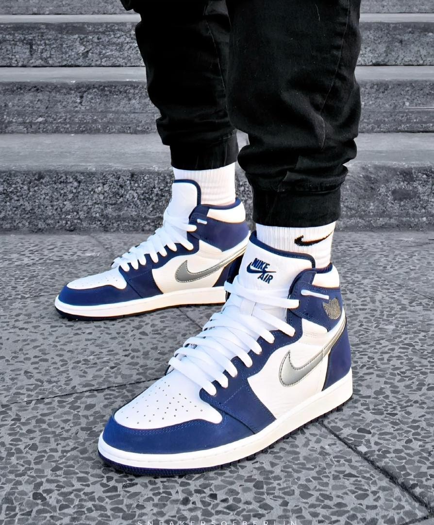 Navy white and gray Air Jordan 1 High sneakers worn on stairs.