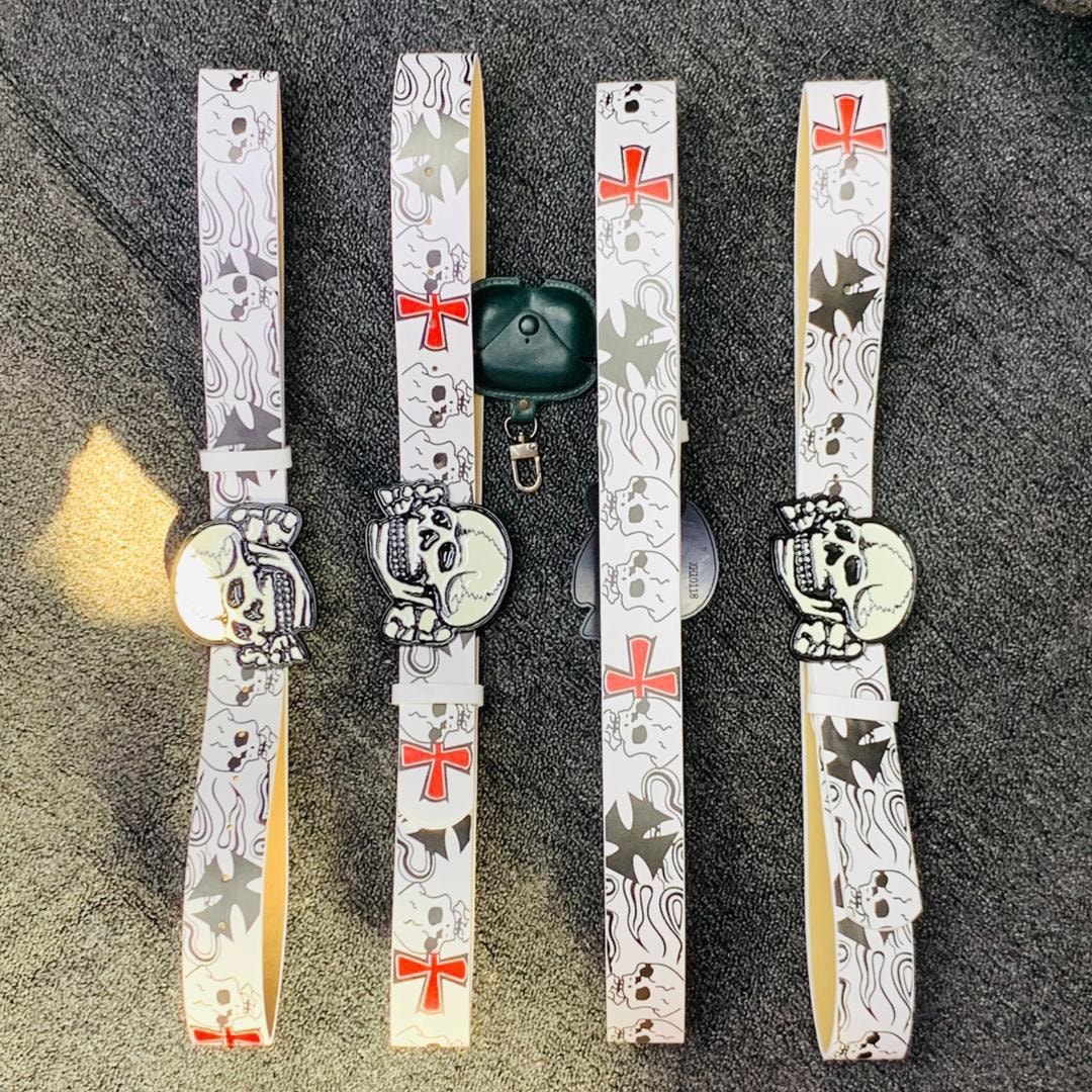 Four white belts with skull and cross prints along with matching skull buckles on a dark background.