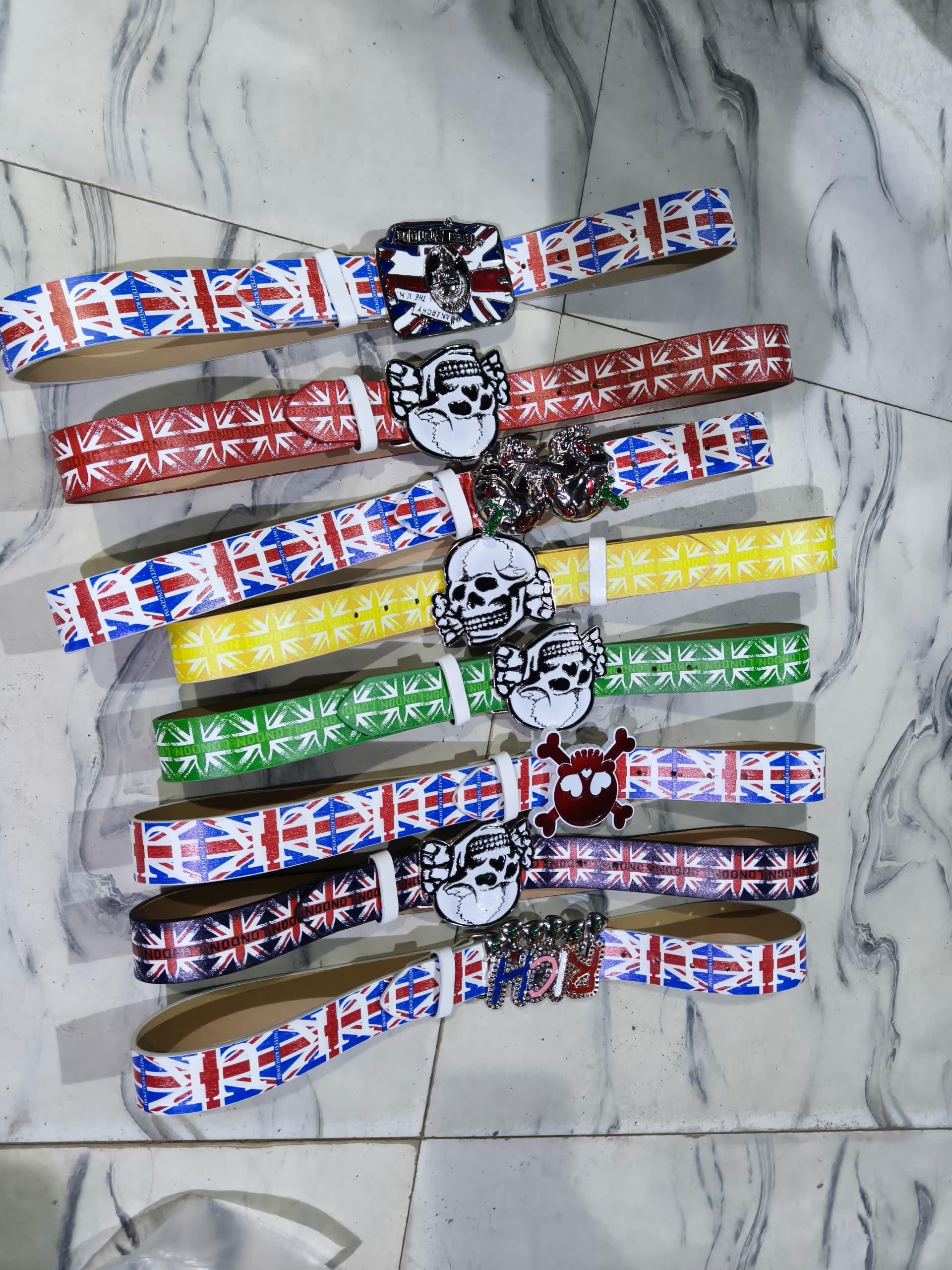Assortment of colorful Union Jack printed belts with skull and decorative buckles in multiple colors.