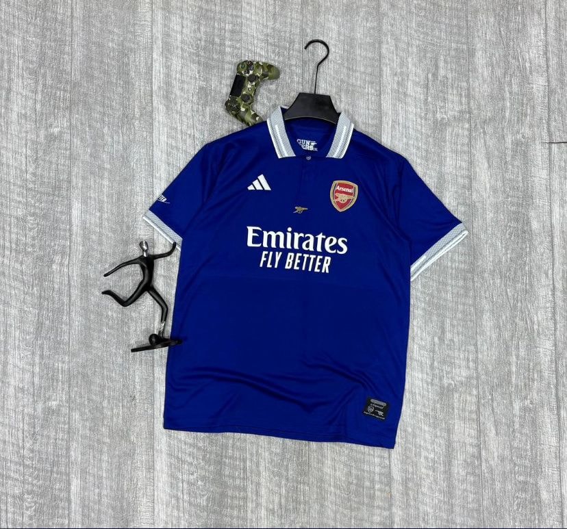 Blue Arsenal Adidas Emirates jersey laid flat with props.
