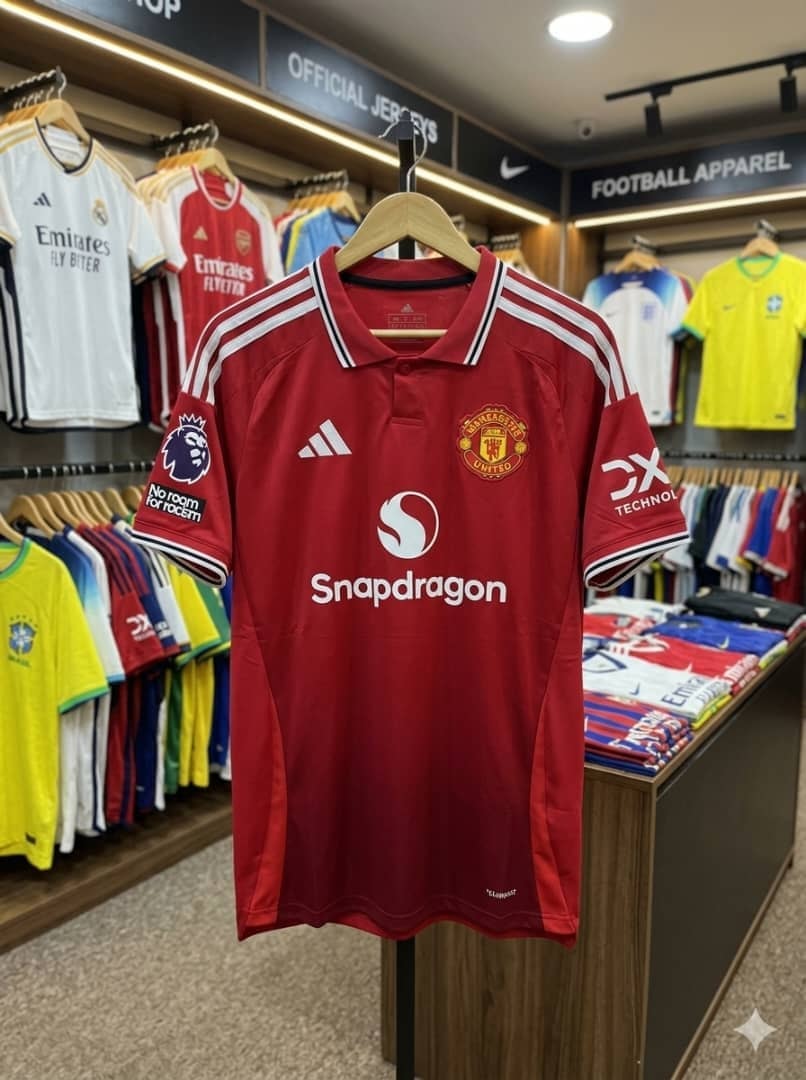 Red Adidas Manchester United jersey on hanger in retail store.