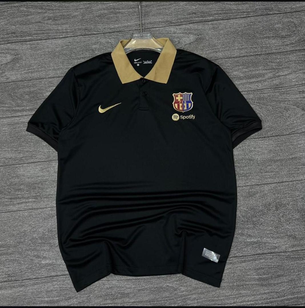 Black Nike FC Barcelona polo jersey laid flat on wooden surface.
