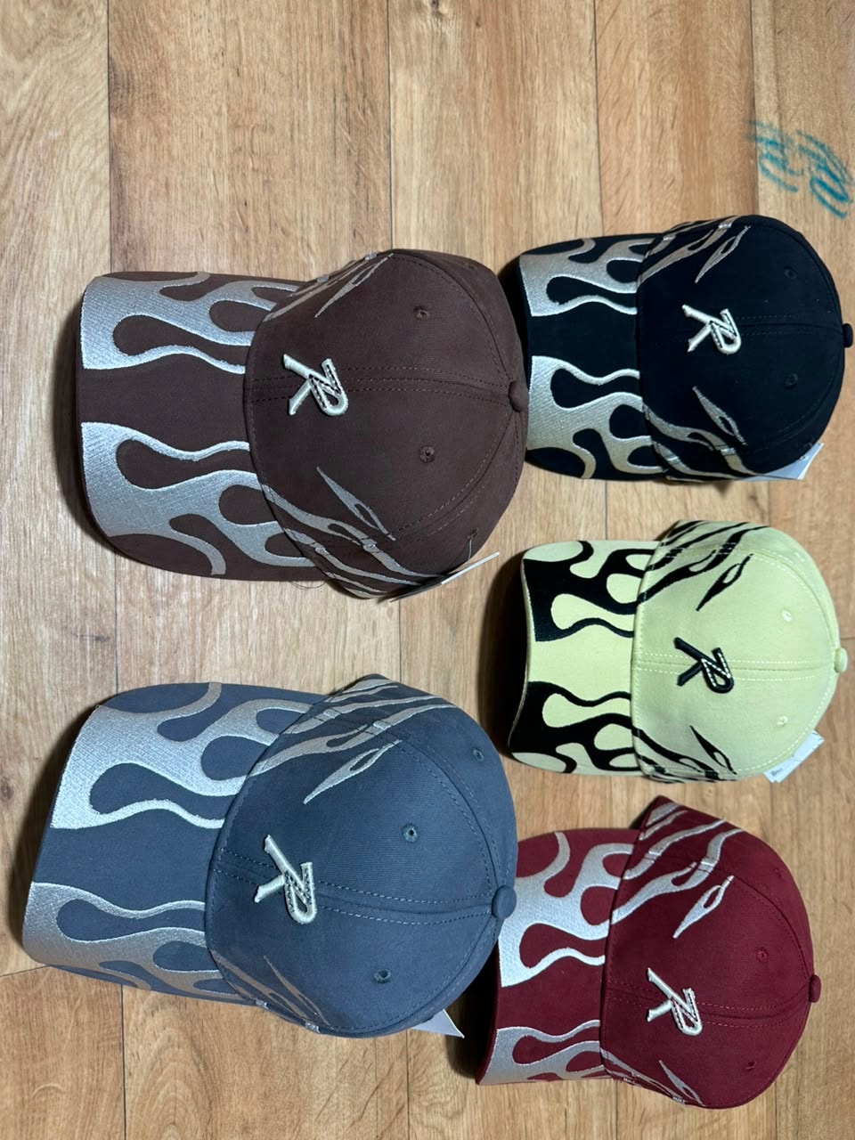 Flame pattern baseball caps with R embroidery in brown, black, gray, lime, and maroon.