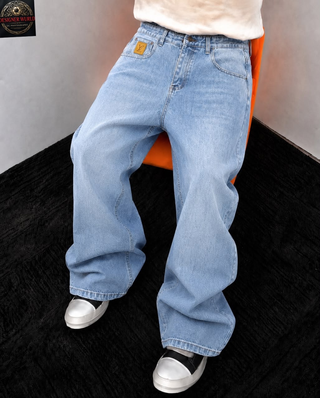 Model wearing light blue baggy jeans with back pocket patch white top and silver shoes.