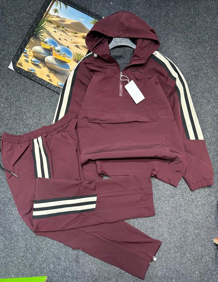 Maroon hooded cargo tracksuit laid flat showing quarter-zip top and striped pants.