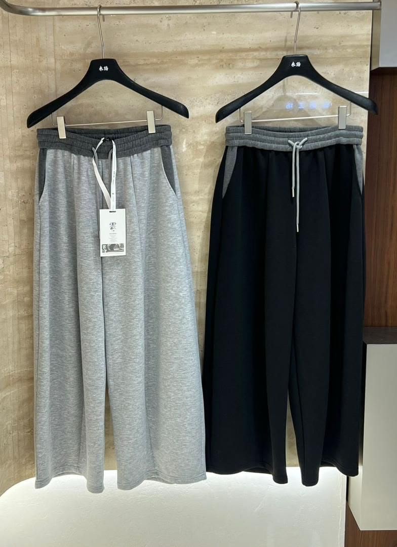Gray and black wide-leg joggers hanging side by side showing contrast waistbands and panels.