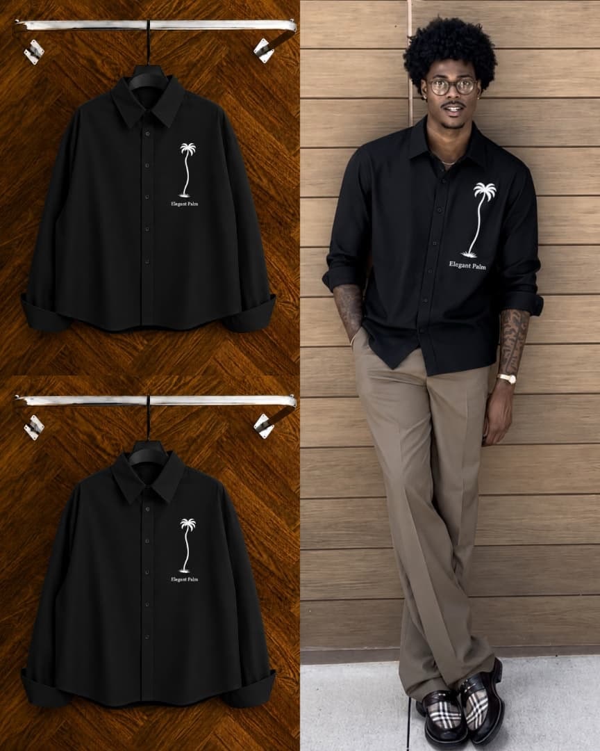 Black shirt with palm tree embroidery and Elegant Palm text on hangers and worn by model against wooden wall.